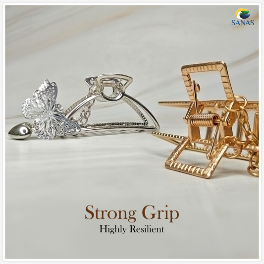 Two hair clips, one silver and one gold, on a light background with 'SANAS' branding.