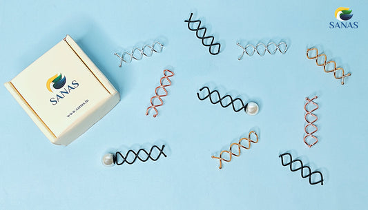 A curated flat lay image showcasing assorted spiral hair pins in black, gold, rose gold, and silver finishes—including single pearl-accented spin pins—on a soft blue background with SANAS branded packaging.
