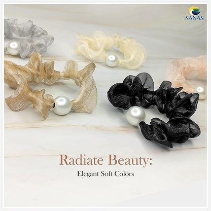 Set of scrunchies in black, beige, and white with pearls on a light wooden surface, featuring the brand 'SANAS'.