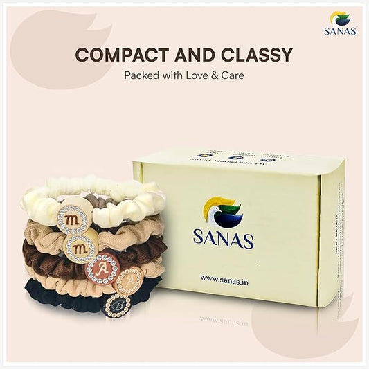 Stack of hair ties with decorative elements next to a box labeled 'SANAS' on a light pink background.